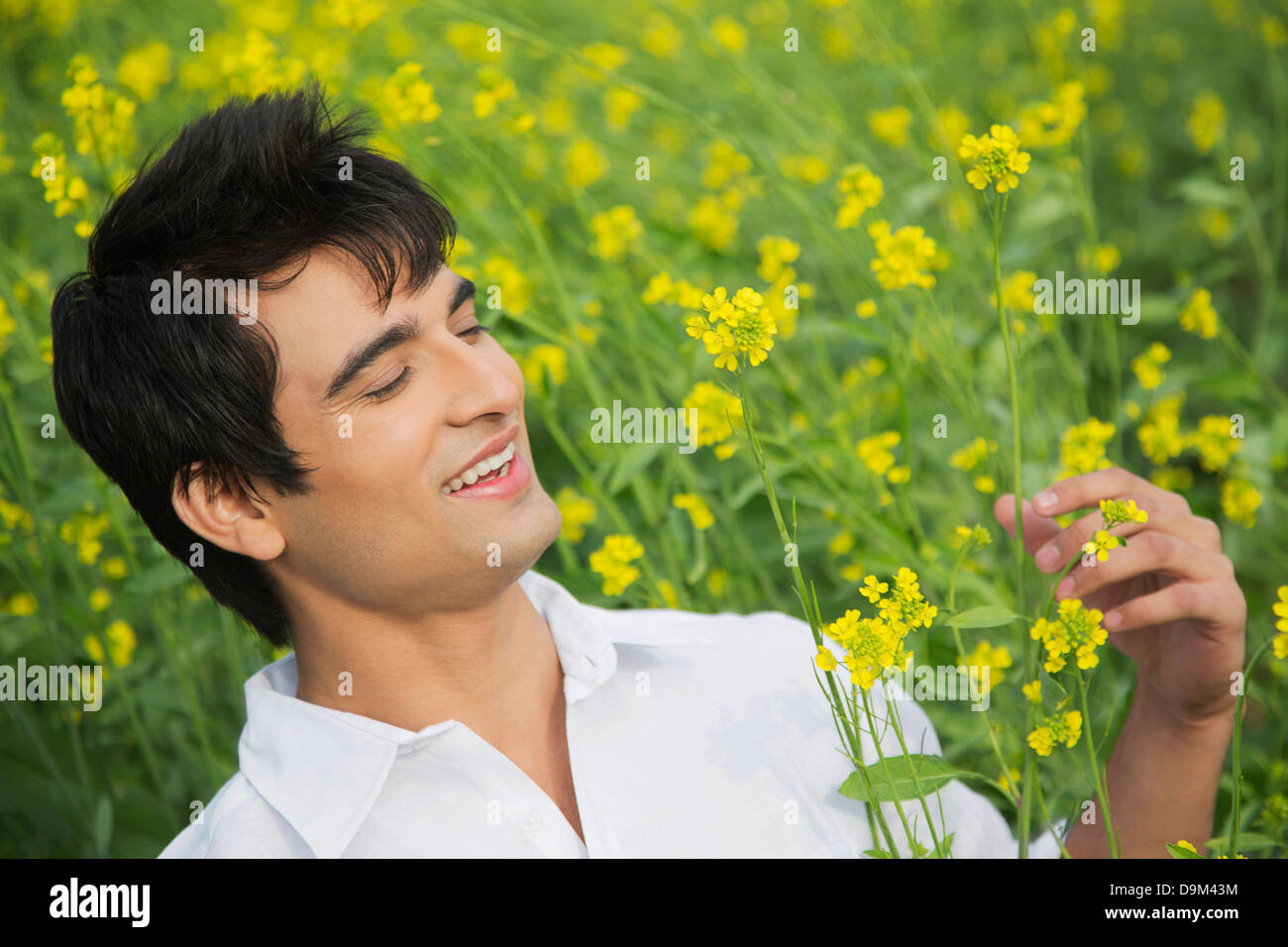 Close-up of a smiling man holding a mustard flower Stock Photo