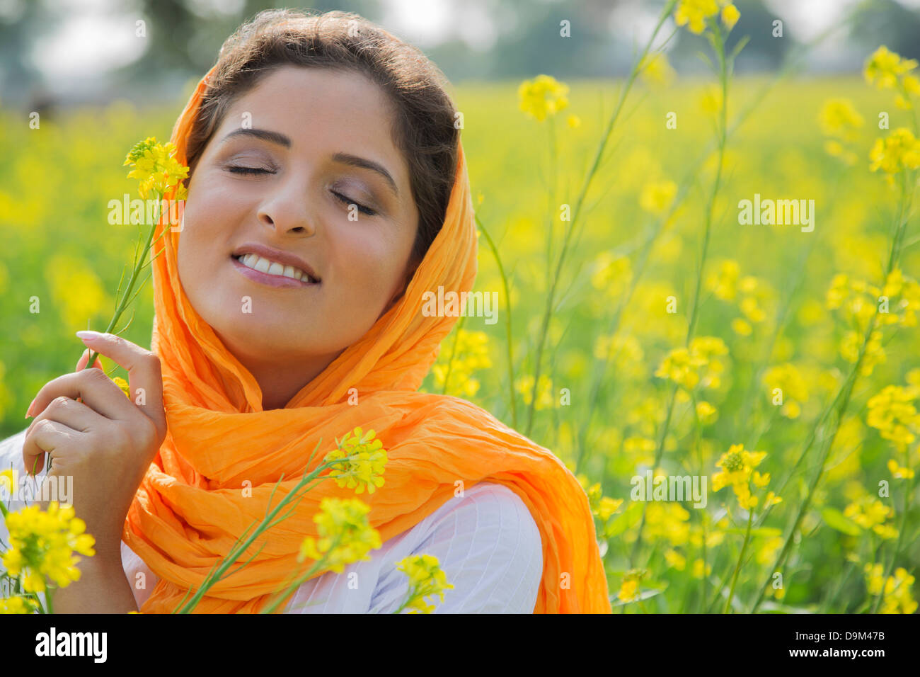 Woman holding mustard flower and smiling Stock Photo