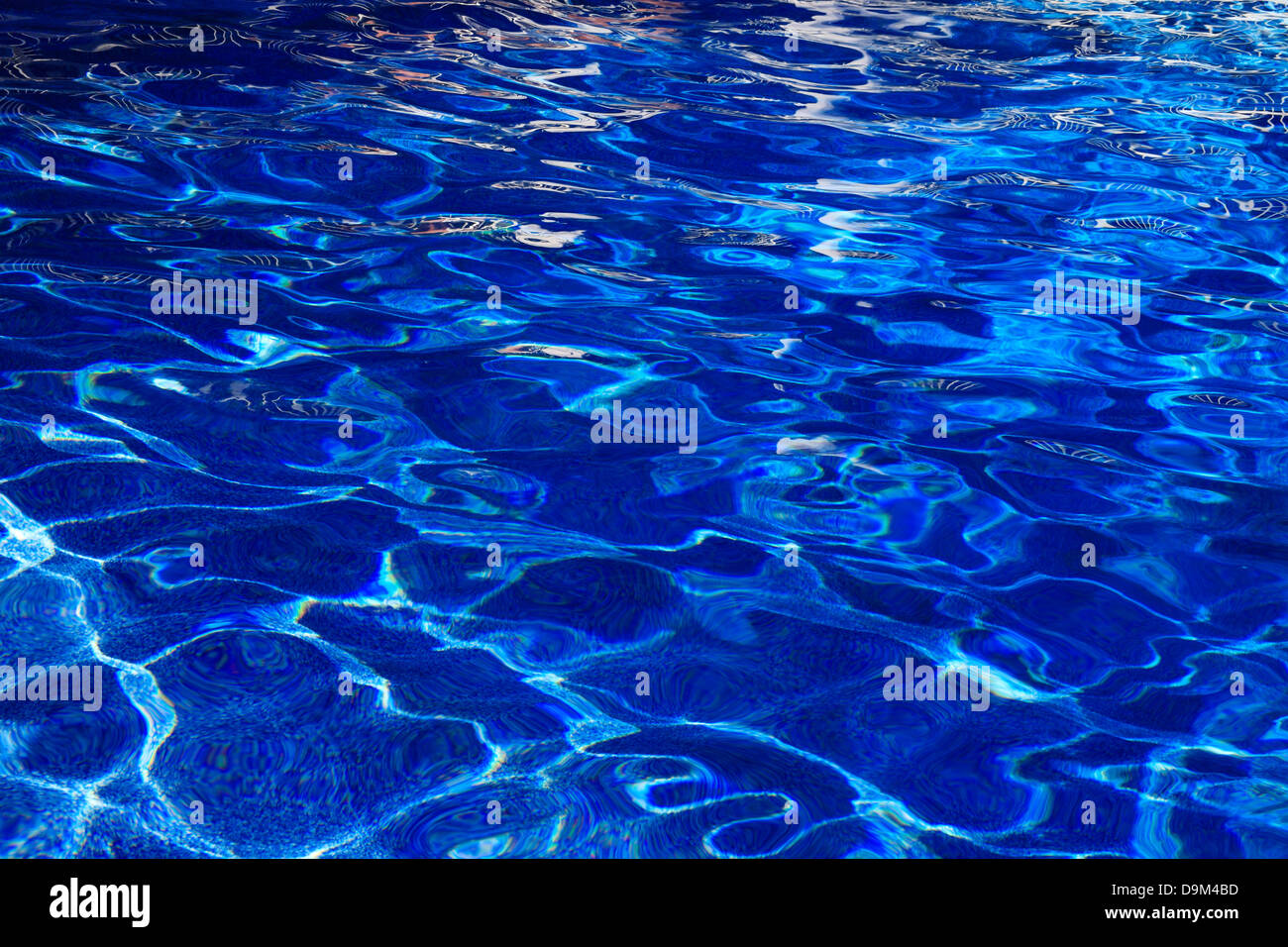 Abstract Patterns Created By Sunlight On The Undulating Surface Of Deep Blue Swimming Pool Water Stock Photo