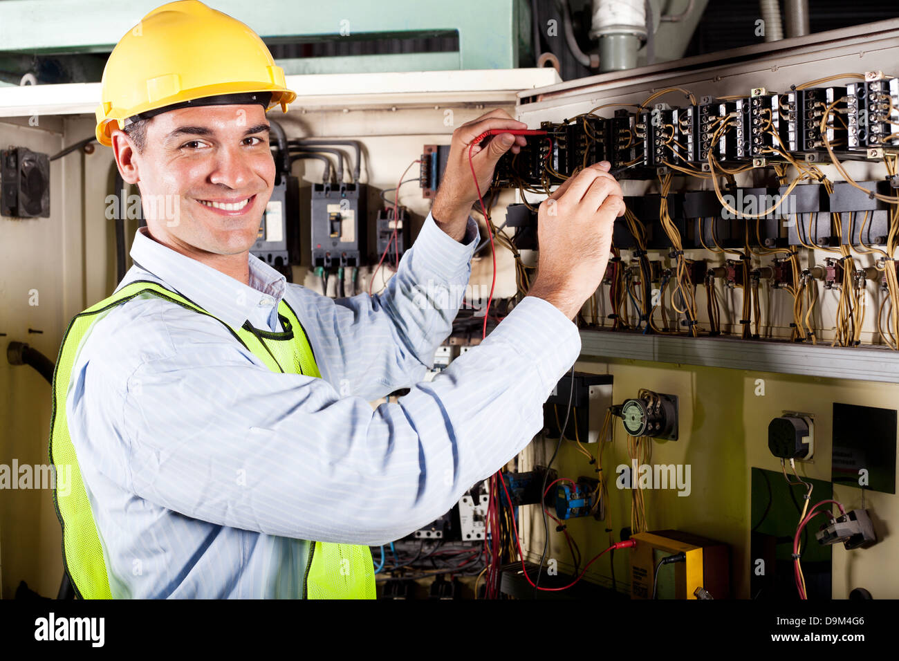 happy male electrician working on industrial machine Stock Photo
