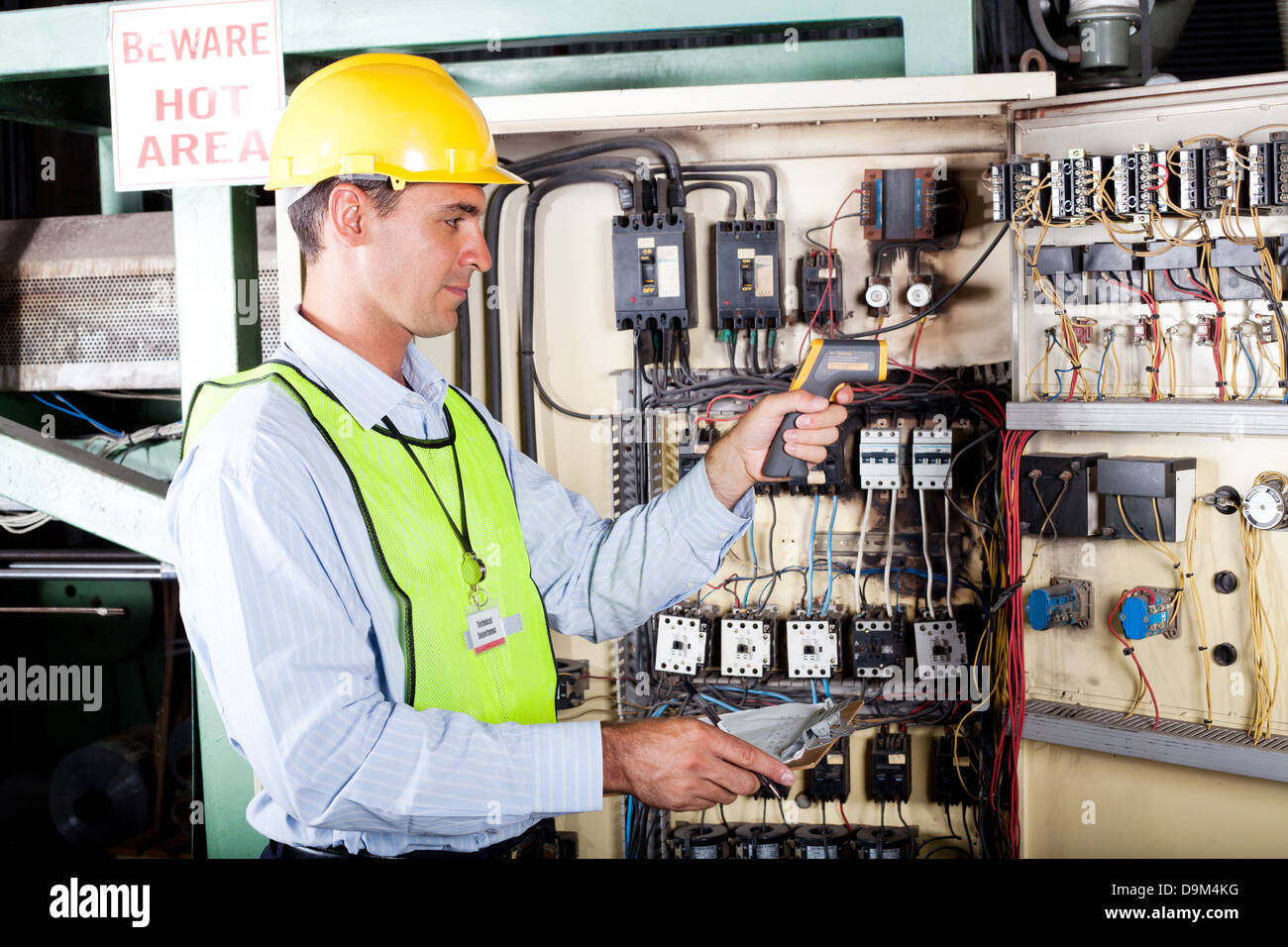 male Caucasian electrician checking industrial machine control box temperature Stock Photo