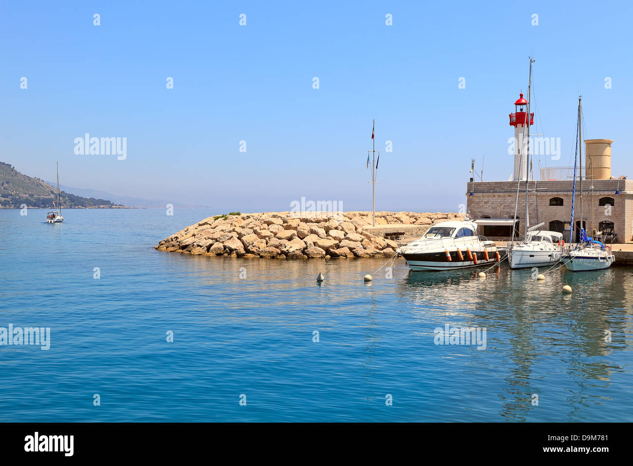 Yachts, boat and small lighthouse at the entrance to marina of Menton - town on french riviera. Stock Photo