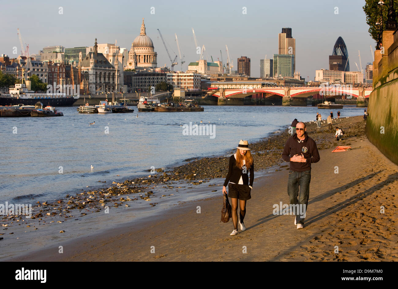 People taking an evening walk on the sandy foreshore of the Thames with the city and Saint Paul's cathedral in the background. Stock Photo