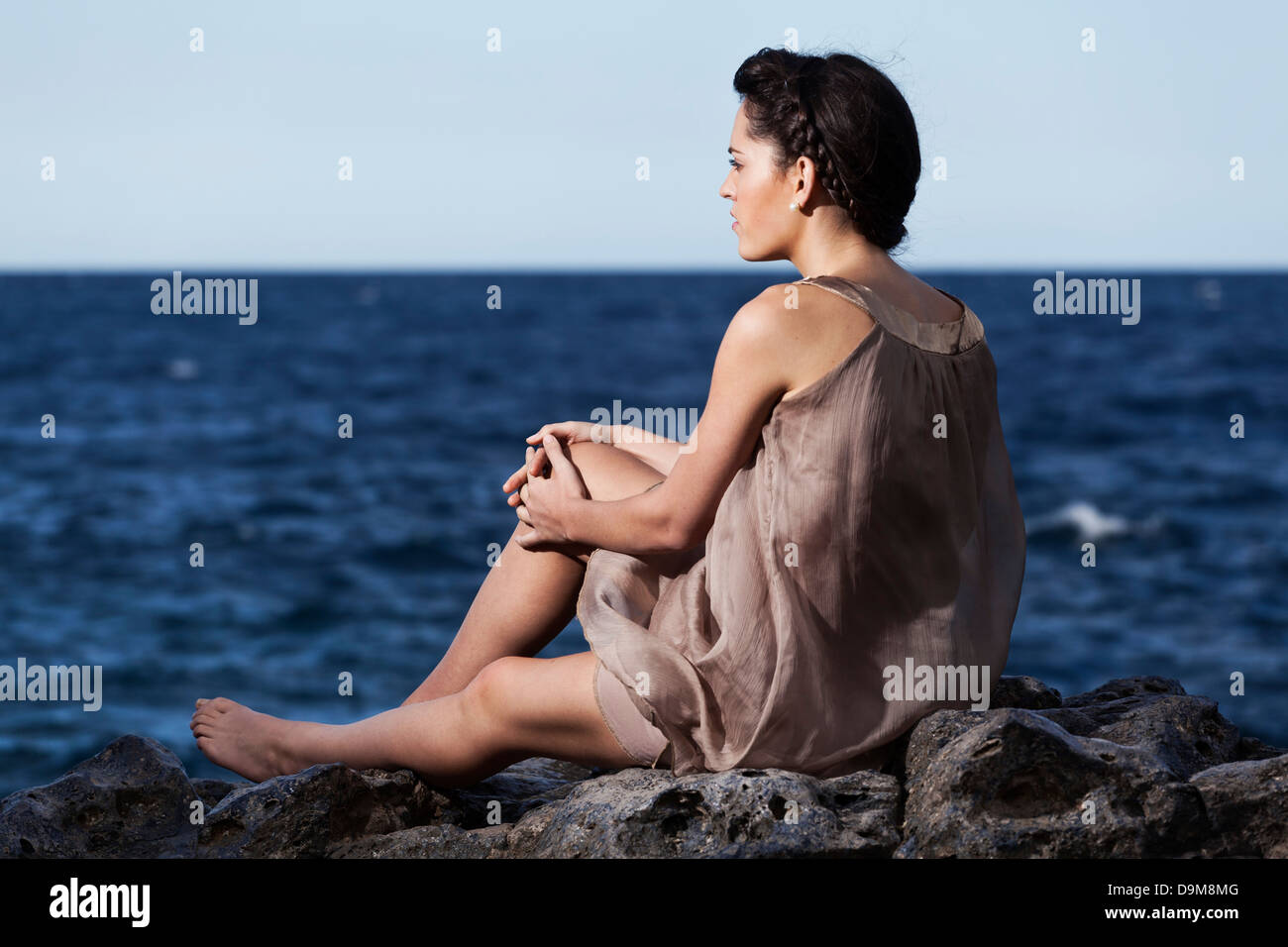 Girl Looking Over Rocks Woman sitting on rocks by sea hi-res stock photography and images - Alamy