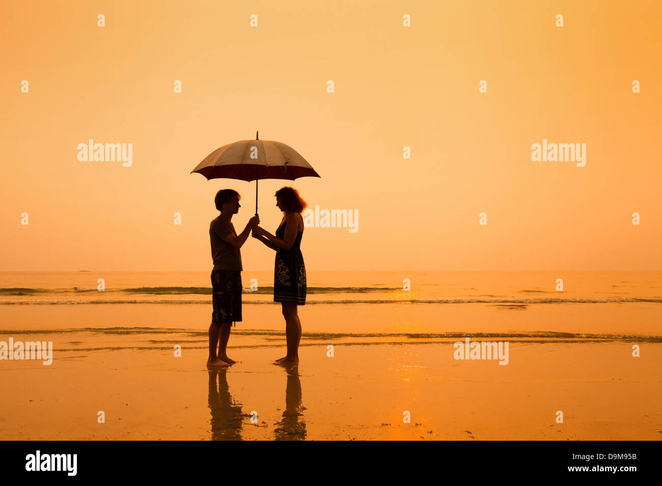 family on the beach, silhouettes of couple with umbrella Stock Photo