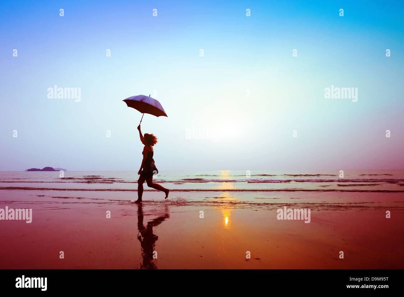 silhouette of happy running woman with umbrella Stock Photo
