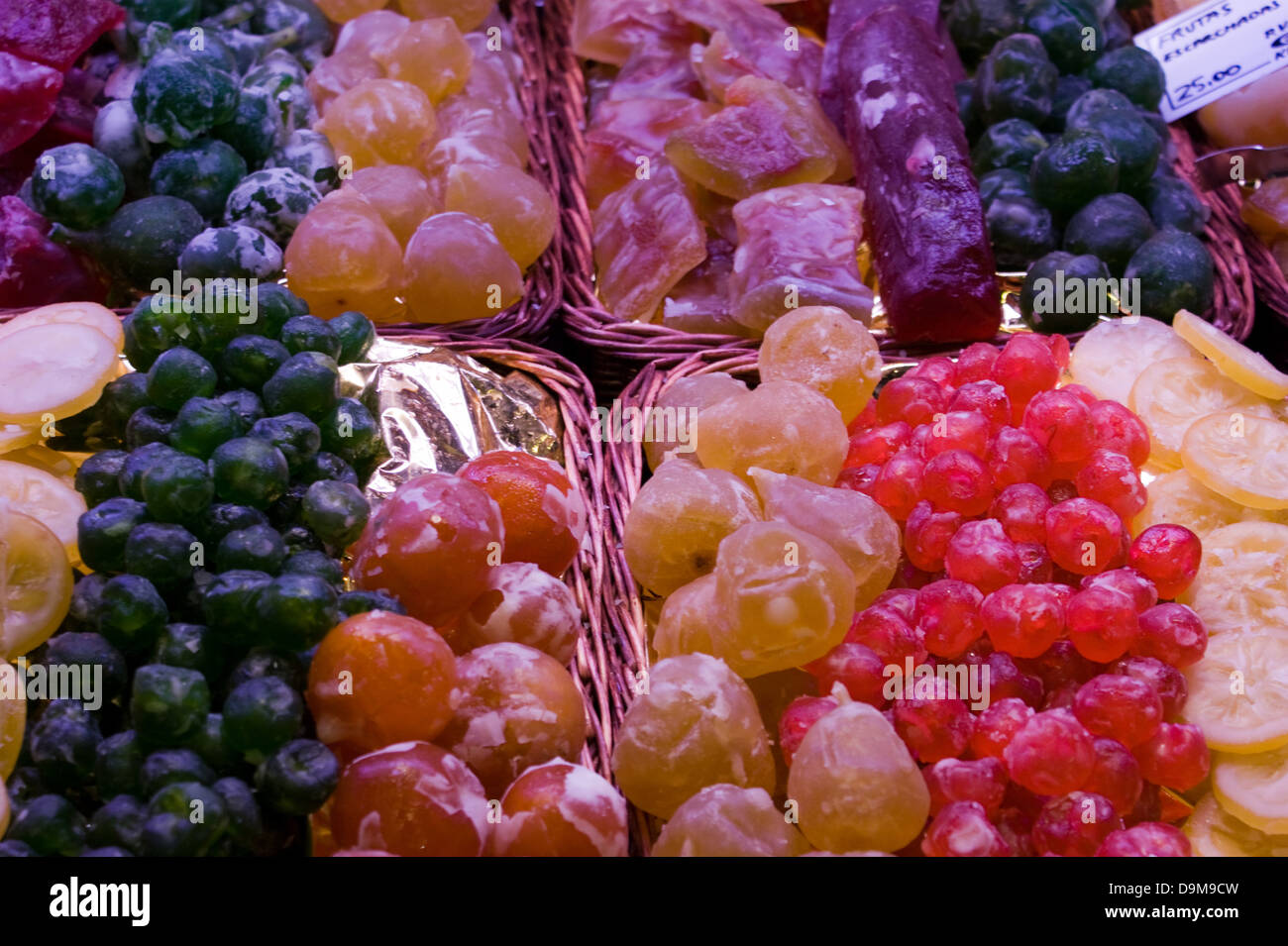 A selection of dried glace fruits displayed in baskets at a stall in La Boqueria Market in Barcelona Spain Stock Photo