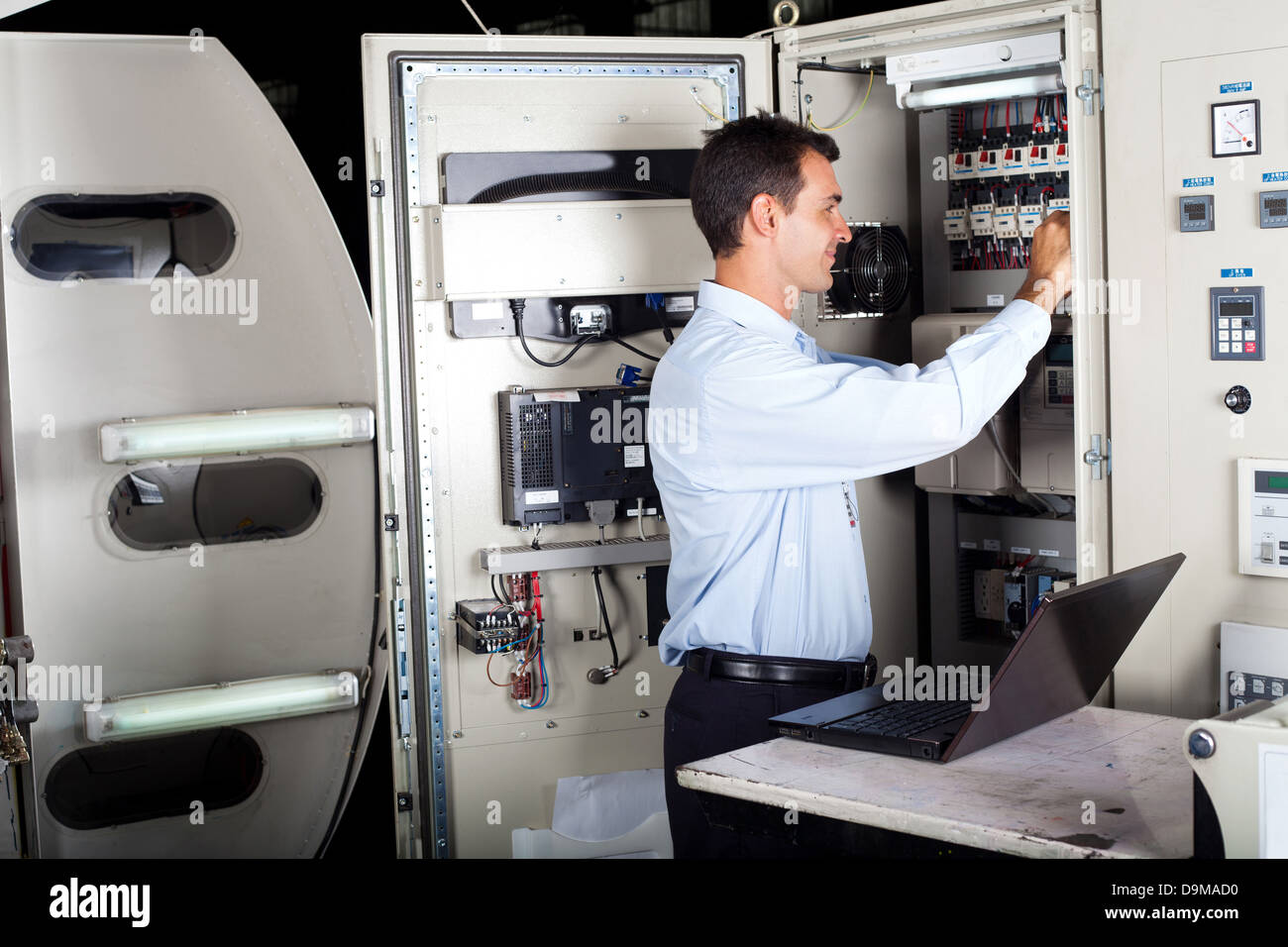 professional technician repairing industrial machine with laptop computer Stock Photo