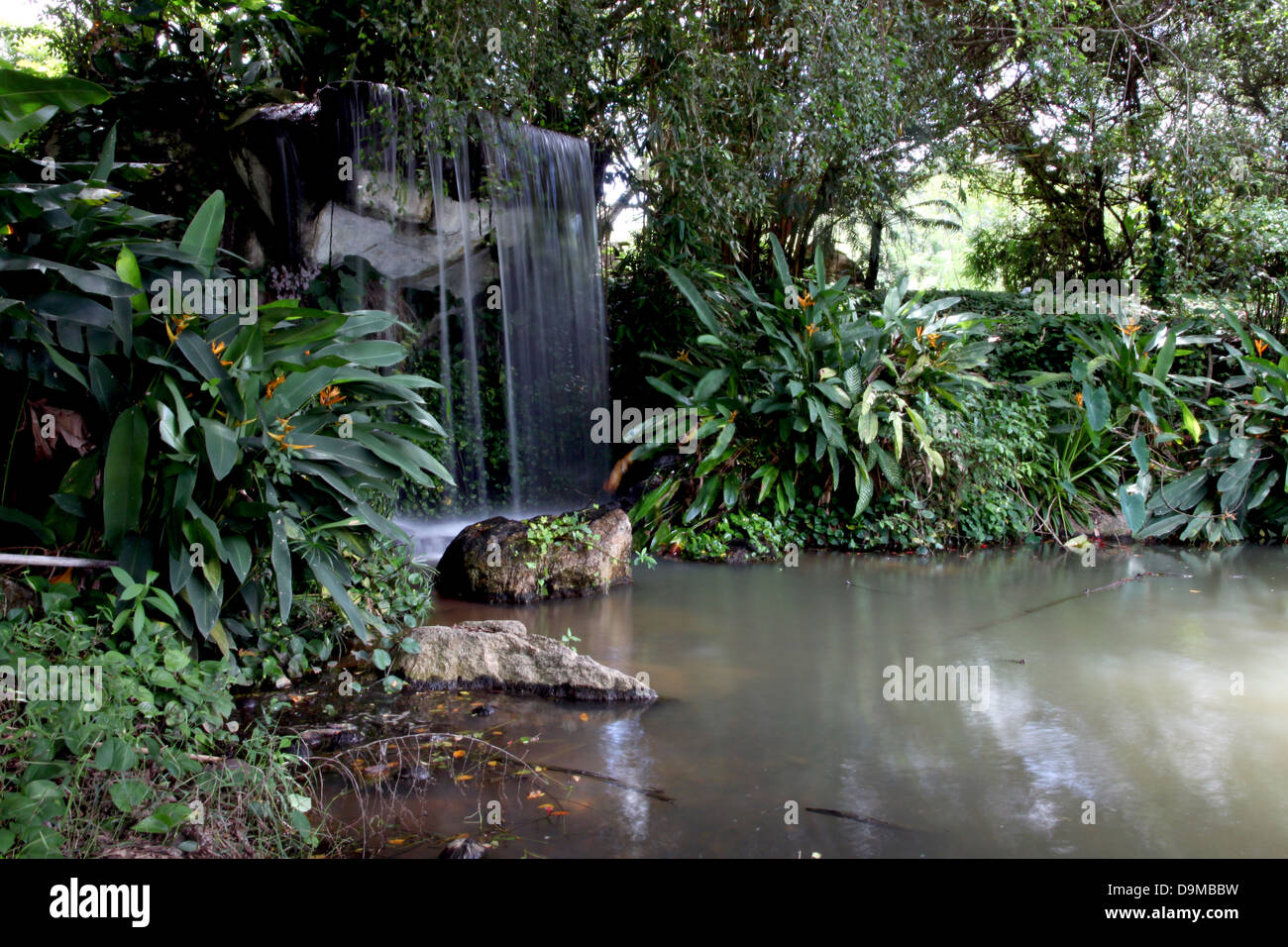 Waterfall in the forest surrounded by orchards around. Stock Photo