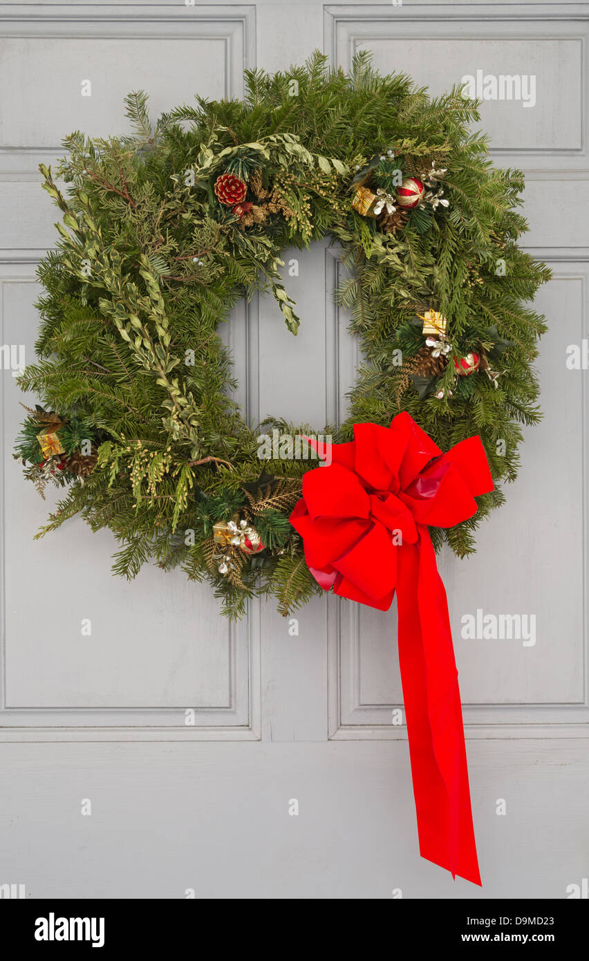 Christmas wreath with red ribbon on a gray door Stock Photo
