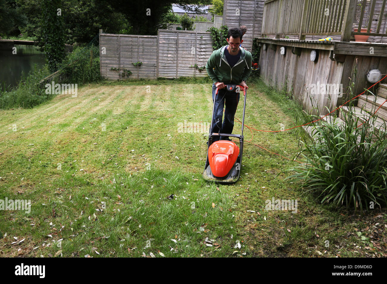 Man Mowing The Lawn With Flymo Lawnmower By River Stour Gillingham Dorset England Stock Photo