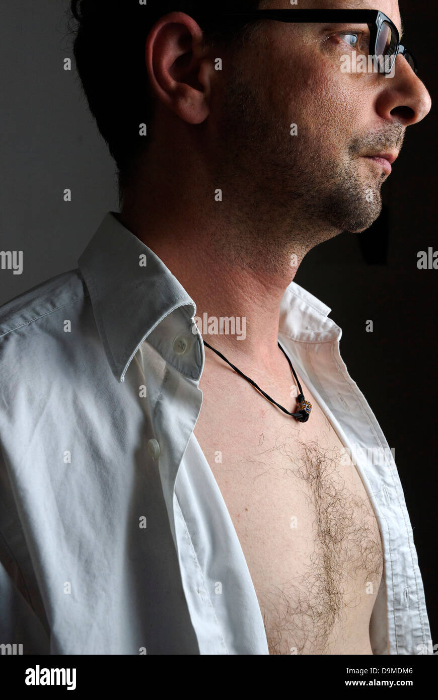 a middle aged man with an open white shirt Stock Photo