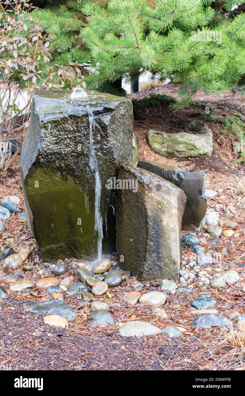 A rocky bubbling water fountain in a courtyard garden Stock Photo Alamy
