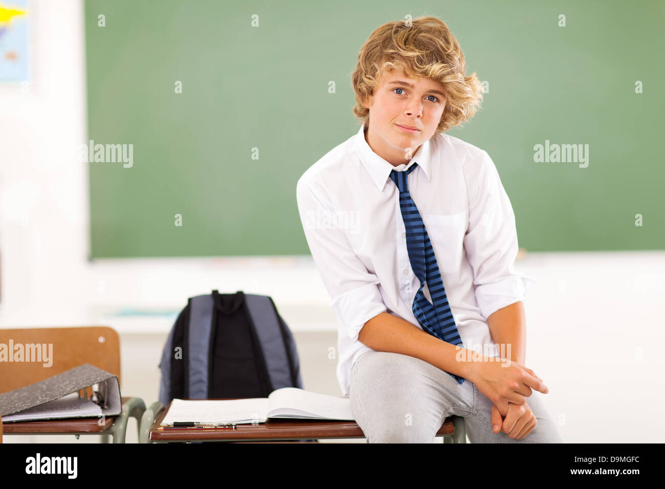high school teen boy student sitting on desk in classroom Stock Photo