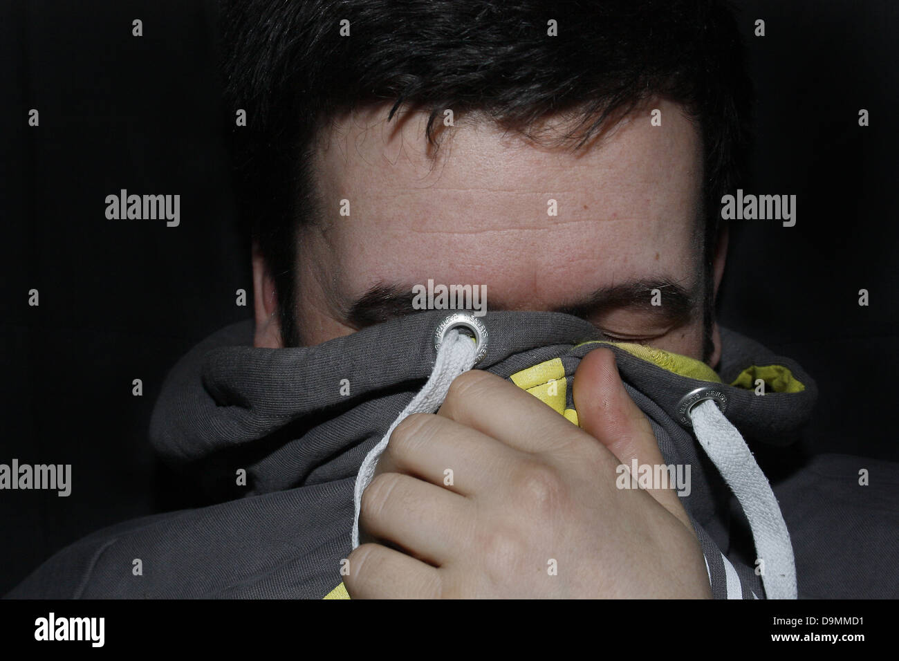 man hiding face with grey hoodie Stock Photo