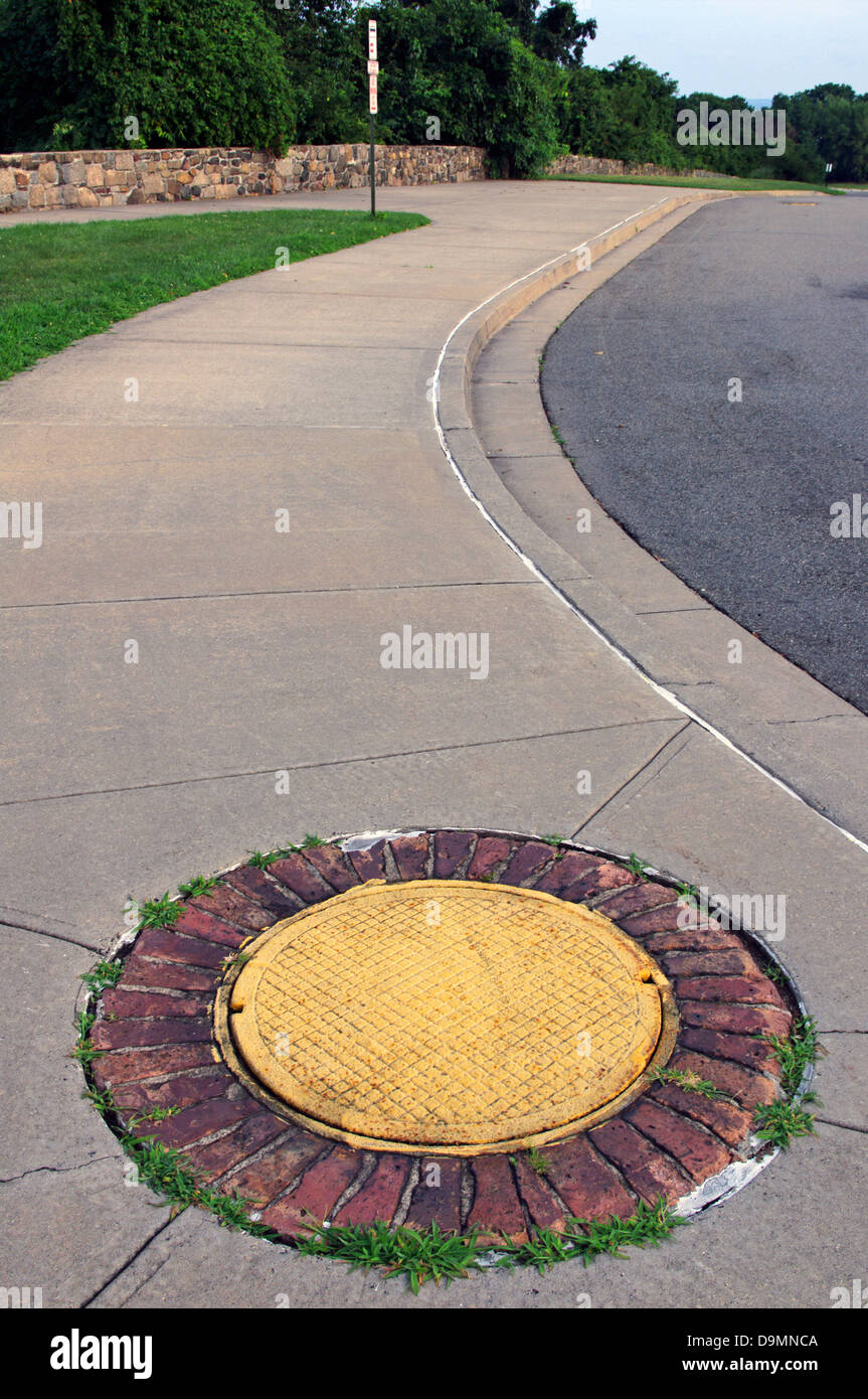 Man hole cover decorated to look like a flower with yellow center and bricks for orange petals in Fort Wadsworth, Staten Island Stock Photo