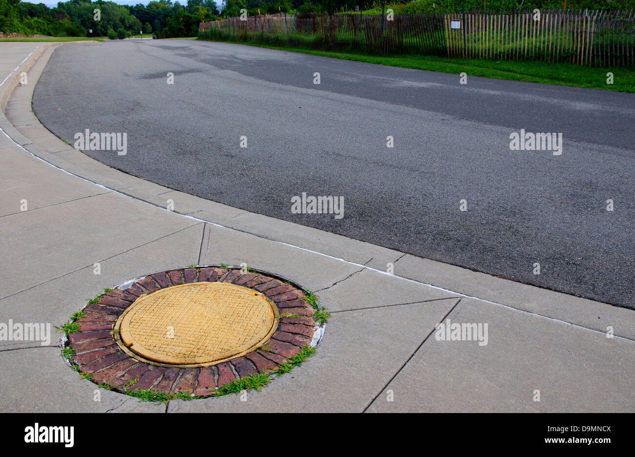 Man hole cover decorated to look like a flower with yellow center and bricks for orange petals in Fort Wadsworth, Staten Island Stock Photo