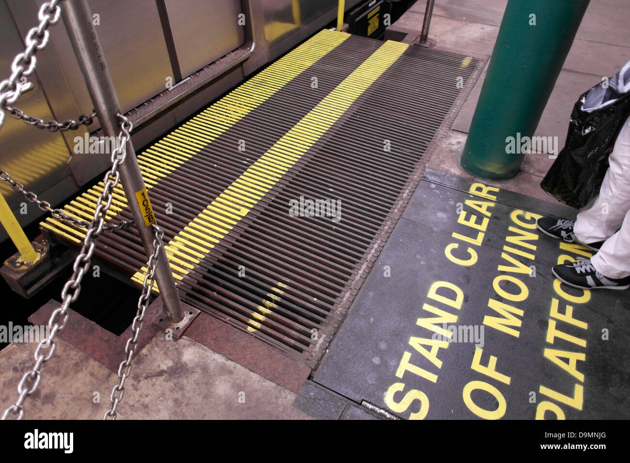 Passenger waiting for the subway gap filler to be in place and the train doors to open, caution 'stand clear of moving platform' Stock Photo