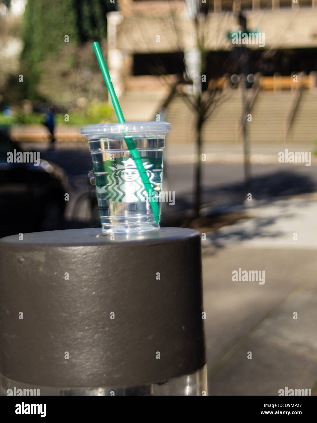 Portland Oregon United States. Starbucks glass with green straw full of water abandoned on the street Stock Photo