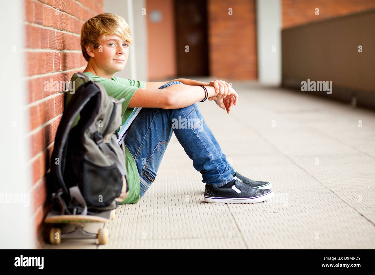 cute male high school student sitting on floor Stock Photo