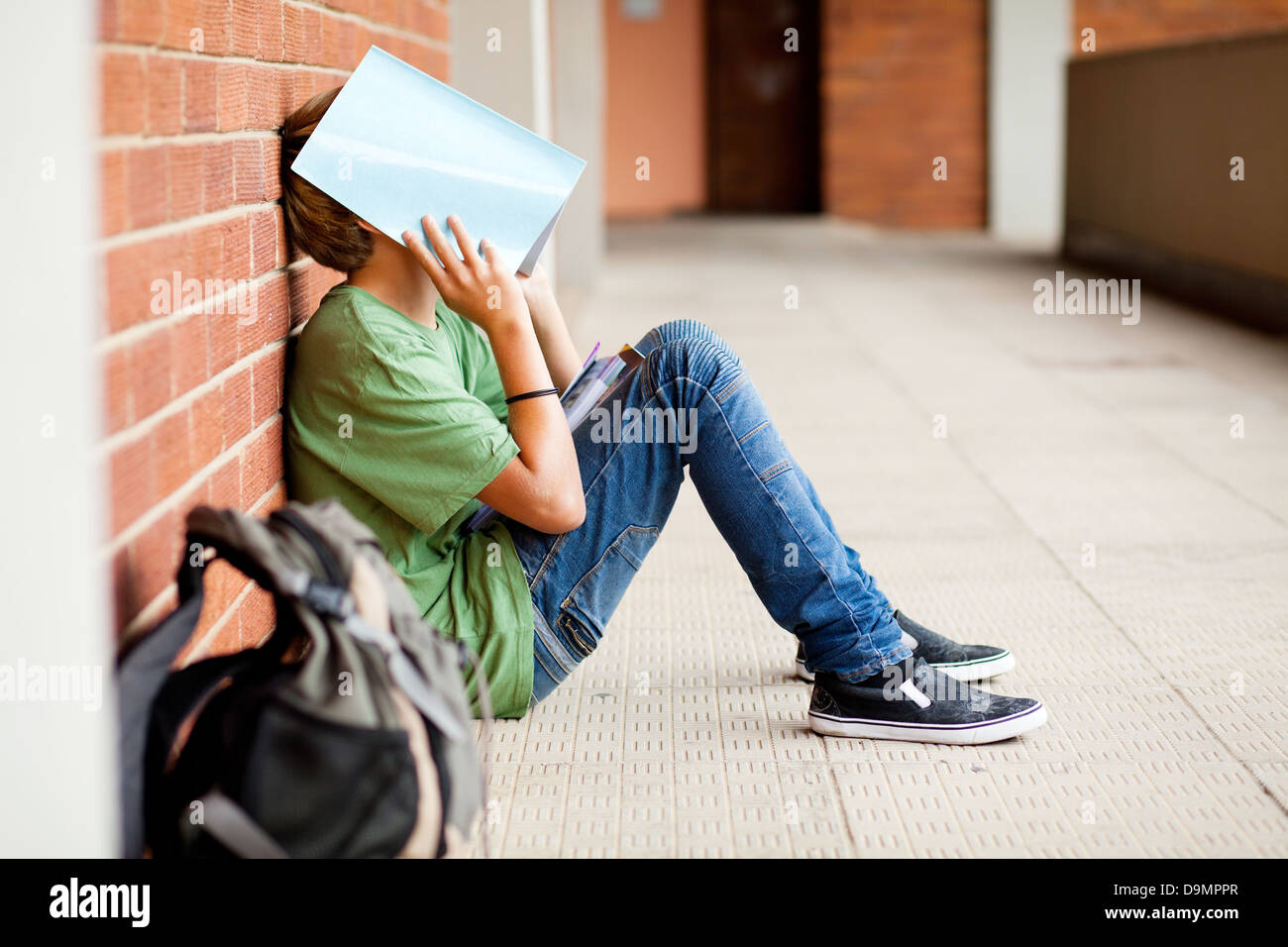 tired high school student using book cover his face Stock Photo