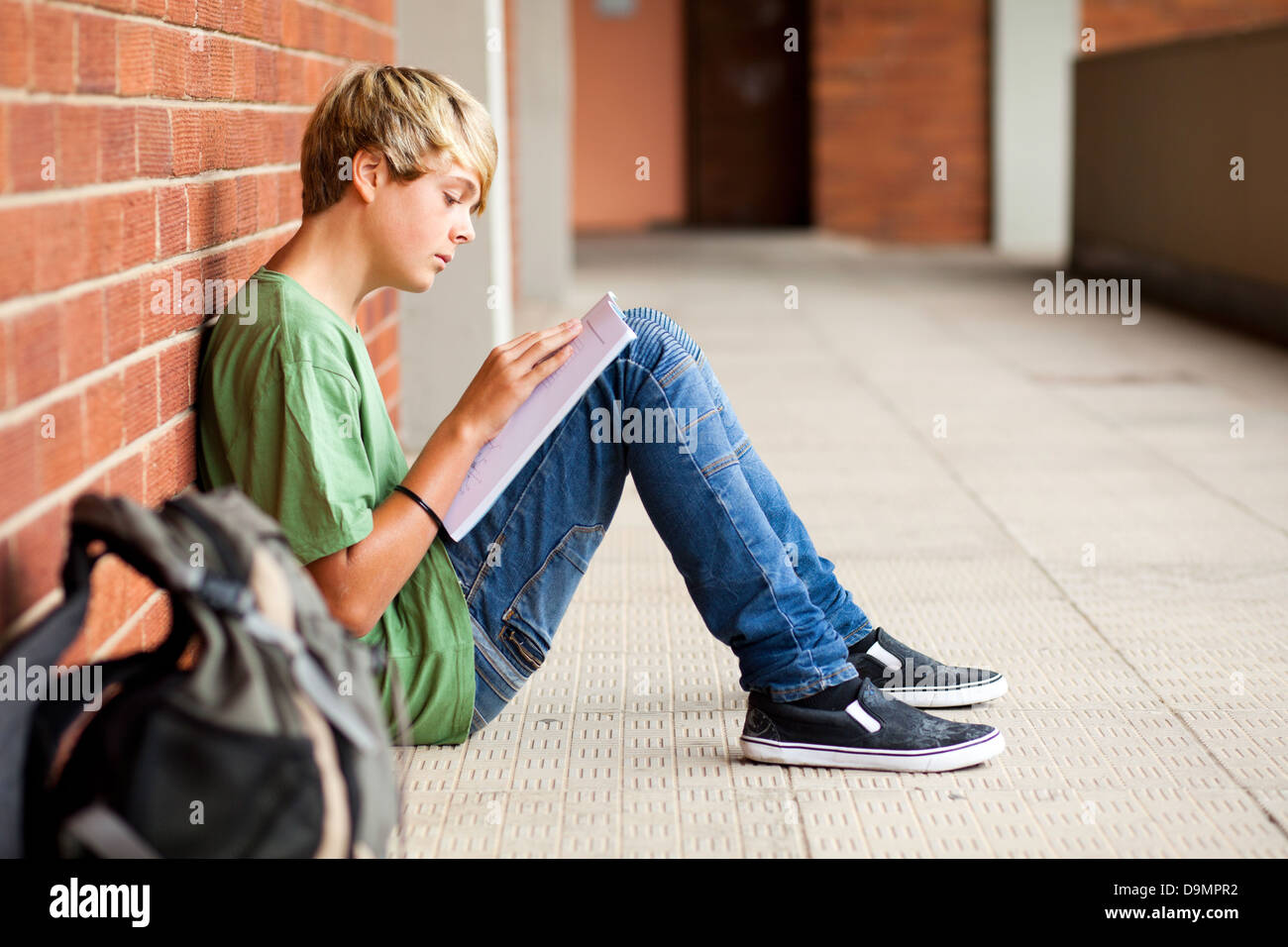 teen high school student reading book in school passage Stock Photo