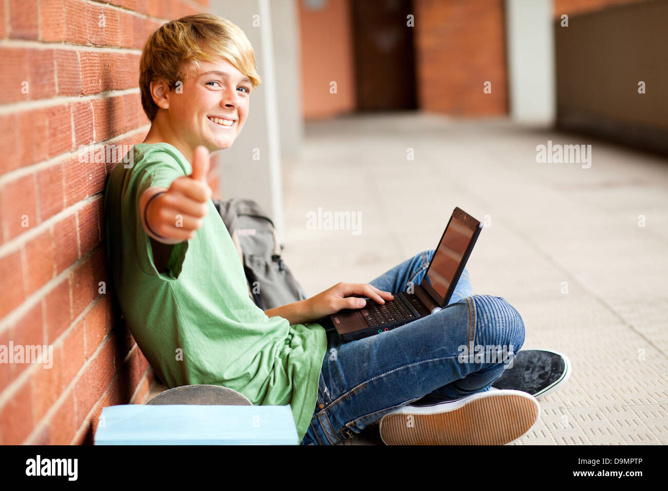 teenage student giving thumb up while using laptop Stock Photo