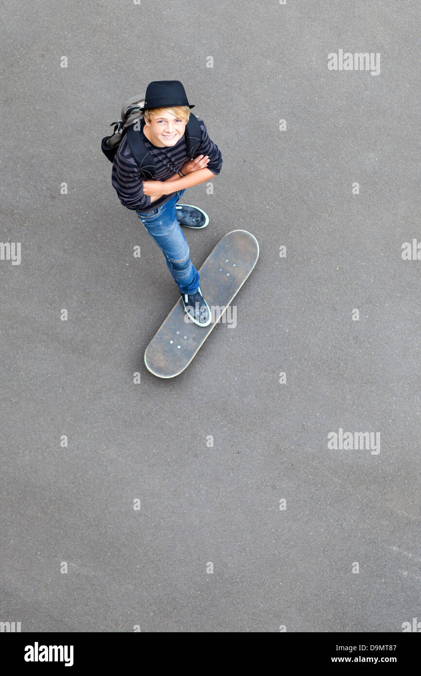 happy teen skateboarder standing on skateboard and looking up Stock Photo