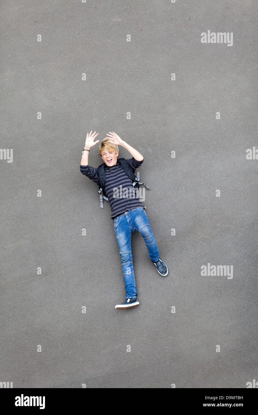 overhead view of a playful teen boy lying on ground Stock Photo