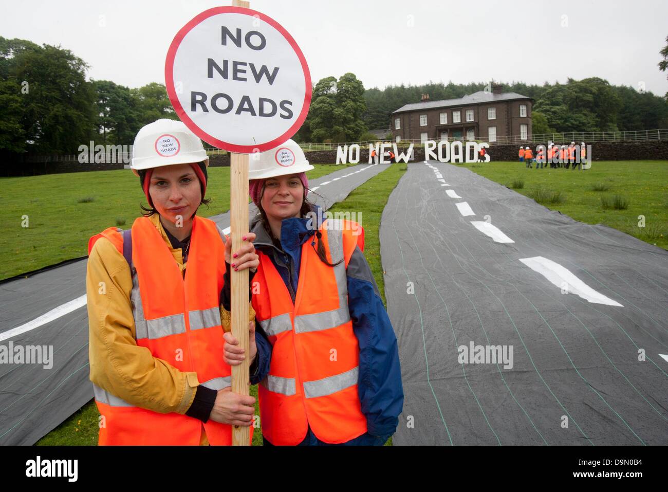 Cheshire, UK. 23 June 2013. Natalie Hynde Daughter of Chrissie Hynde and Ray Davies and Gabriele join 20 activists dressed in roadbuilders' high viz clothing rolling out a fake road in the field immediately below Crag Hall, Cheshire in whose grounds the Chancellor of the exchequer George Osborne has a residence. The protest was made to highlight the expected release of money for roadbuilding schemes throughout  the UK in the imminent spending reivew on Wednesday 26th June Credit:  adrian arbib/Alamy Live News Stock Photo