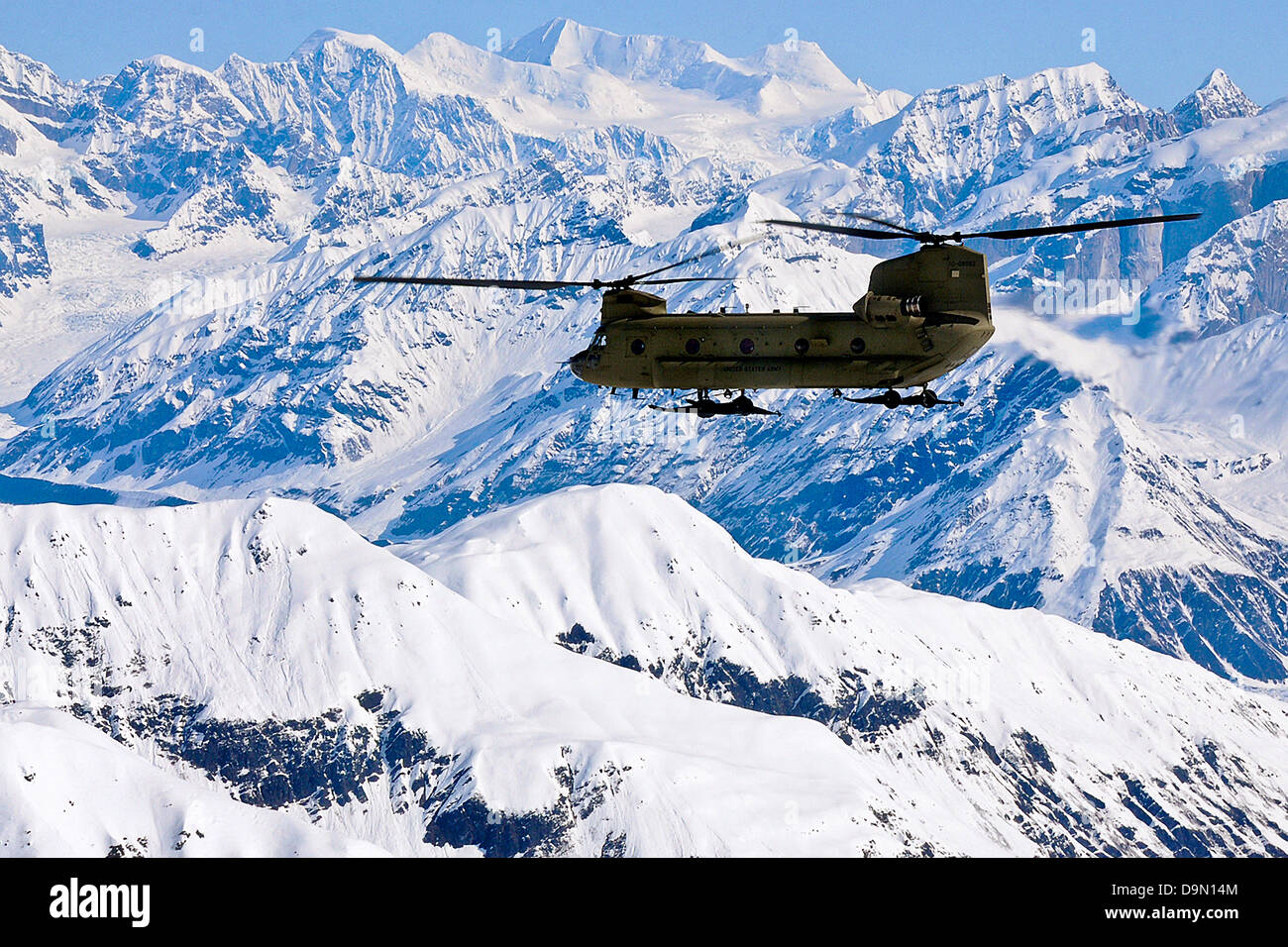 A US Army CH-47 Chinook helicopter flies along the Alaska Range on its way to Kahiltna Glacier May 20, 2013. A team of eight soldiers and one Army civilian from Fort Wainwright were transported to the National Park Service base camp on the glacier to begin their attempt to climb Mount McKinley, North America's tallest peak. Stock Photo