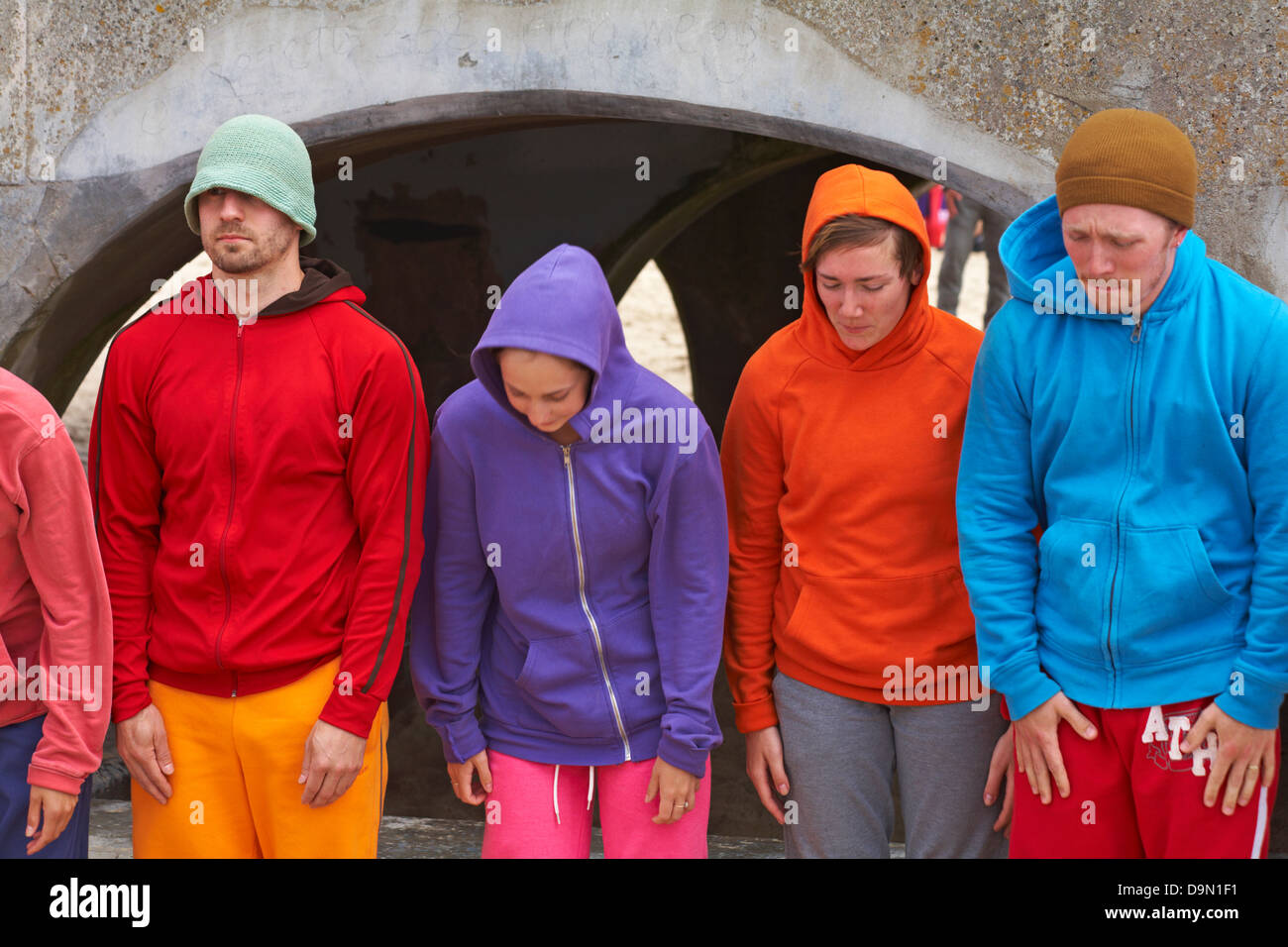 Bodies in Urban Spaces performers in colourful hoodies standing by Bournemouth Pier, Dorset UK at the end of their performance in June Stock Photo