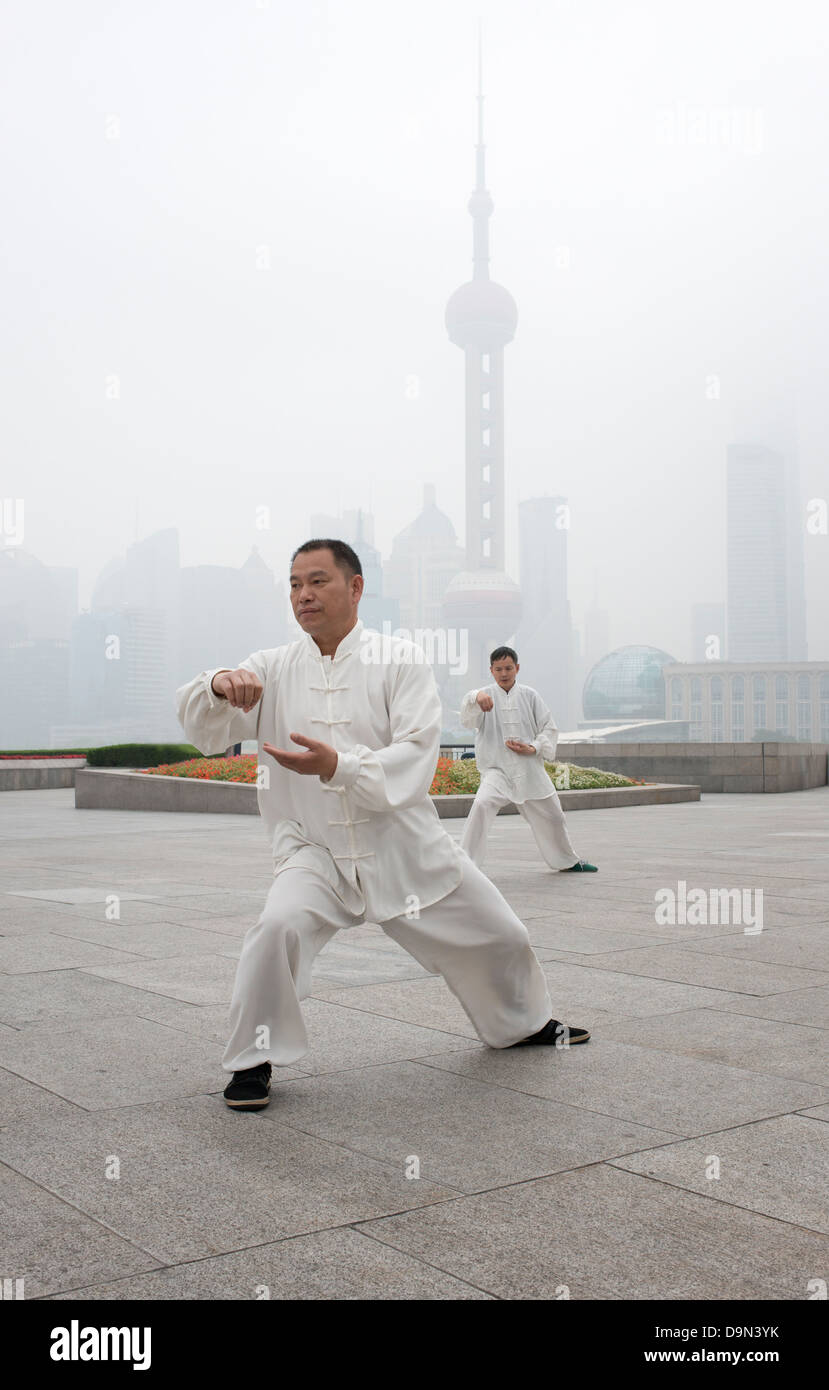 Two Men performing Tai Chi exercises early in the morning on the Bund ...