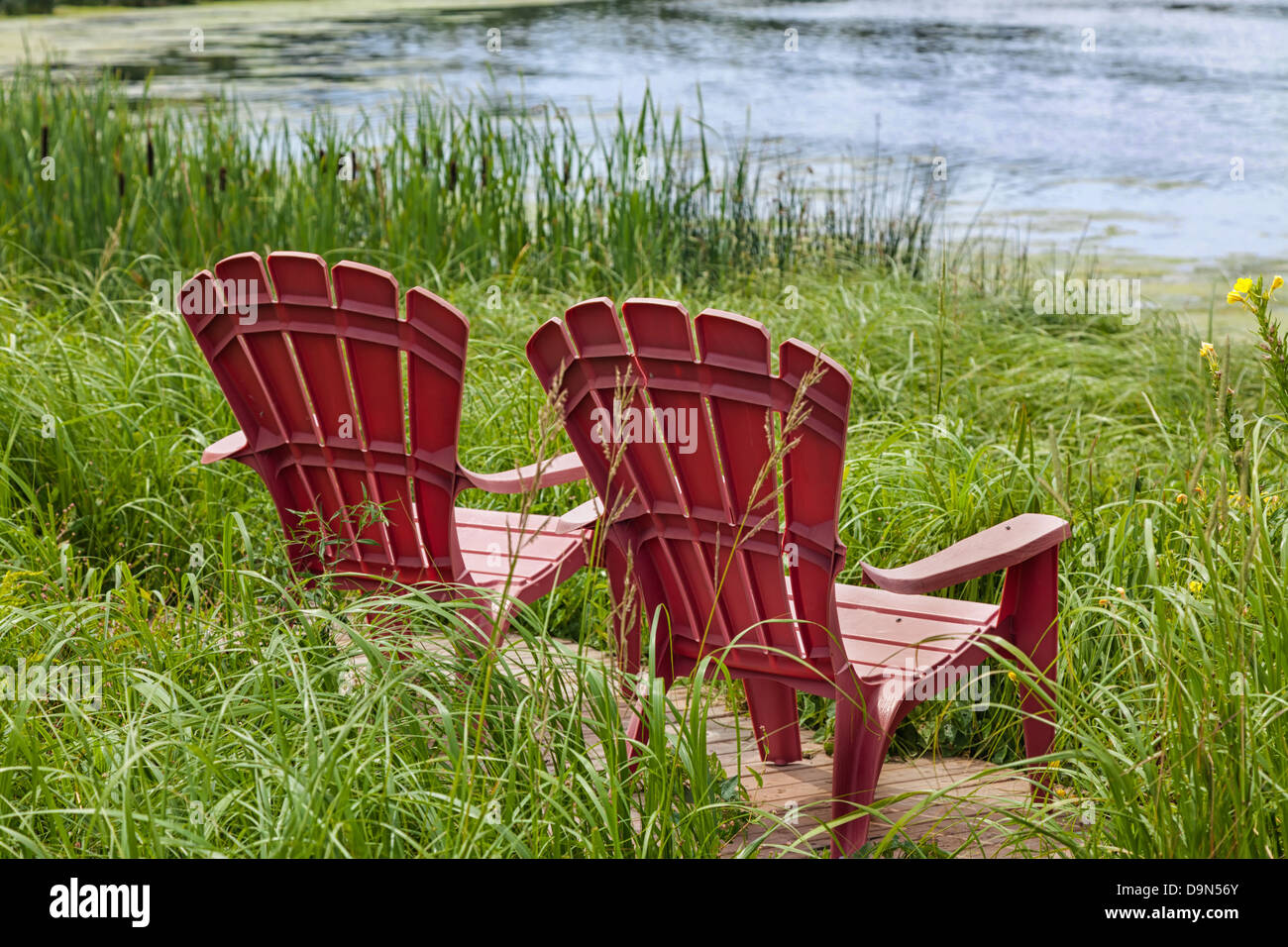 Red plastic Adirondack chairs placed for a view of the