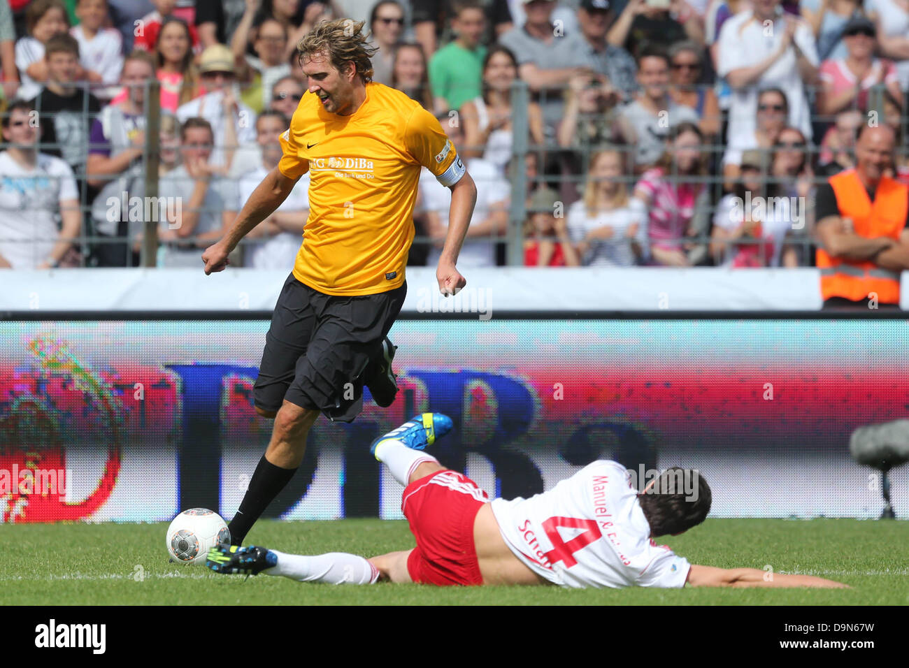 Basketball player Dirk Nowitzki (L) vies for the ball with Marcel Schaefer (ground) during the benefit soccer match between team Manuel Neuer & Friends and Nowitzki Allstars in Wuerzburg, Germany, 23 June 2013. The proceeds from the even go to the project 'Football meets Culture' of the international campaign LitCam. Photo: DANIEL KARMANN Stock Photo