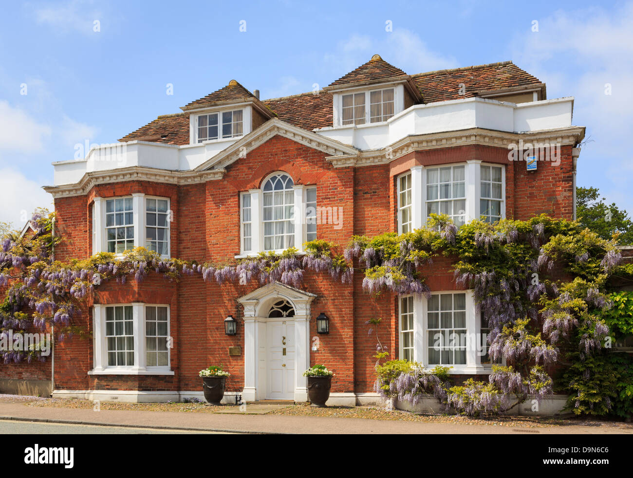 Wisteria floribunda growing around a redbrick detached house