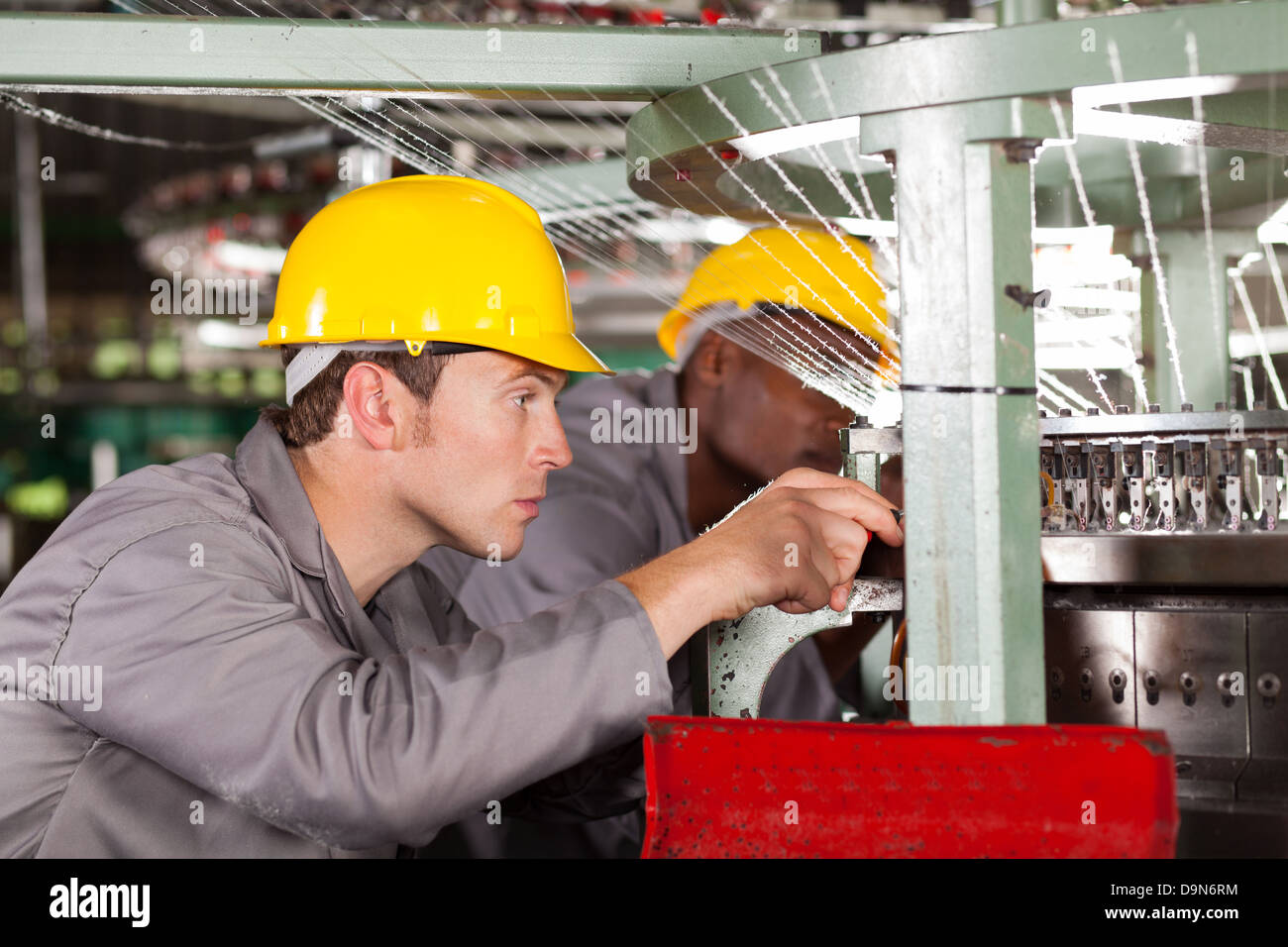 two textile weaving machine mechanics repairing loom Stock Photo