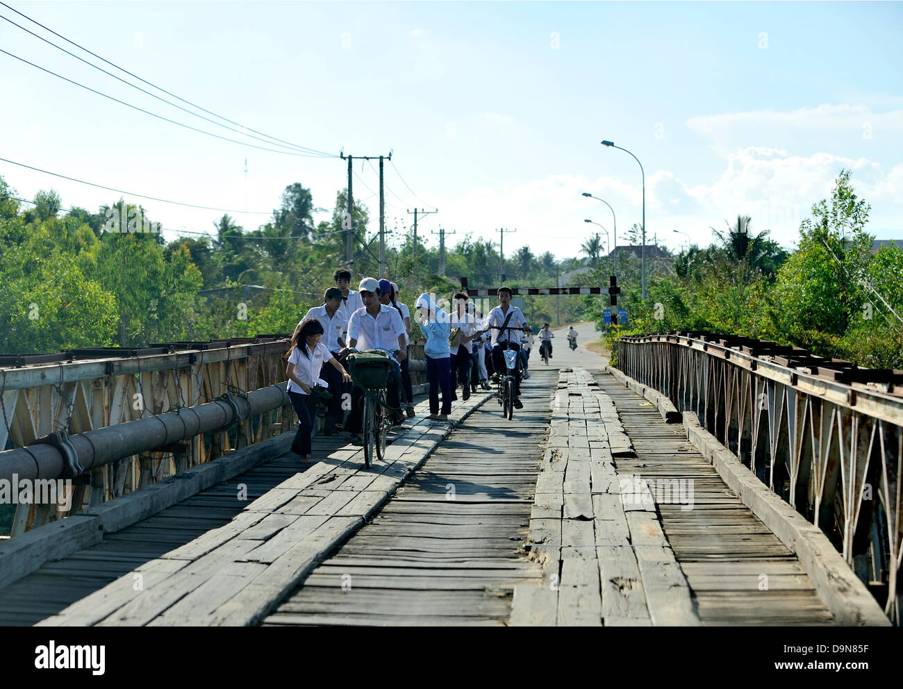 School children crossing a very old and now very rare wooden-paved traffic bridge, Binh Thuan province, Vietnam Stock Photo