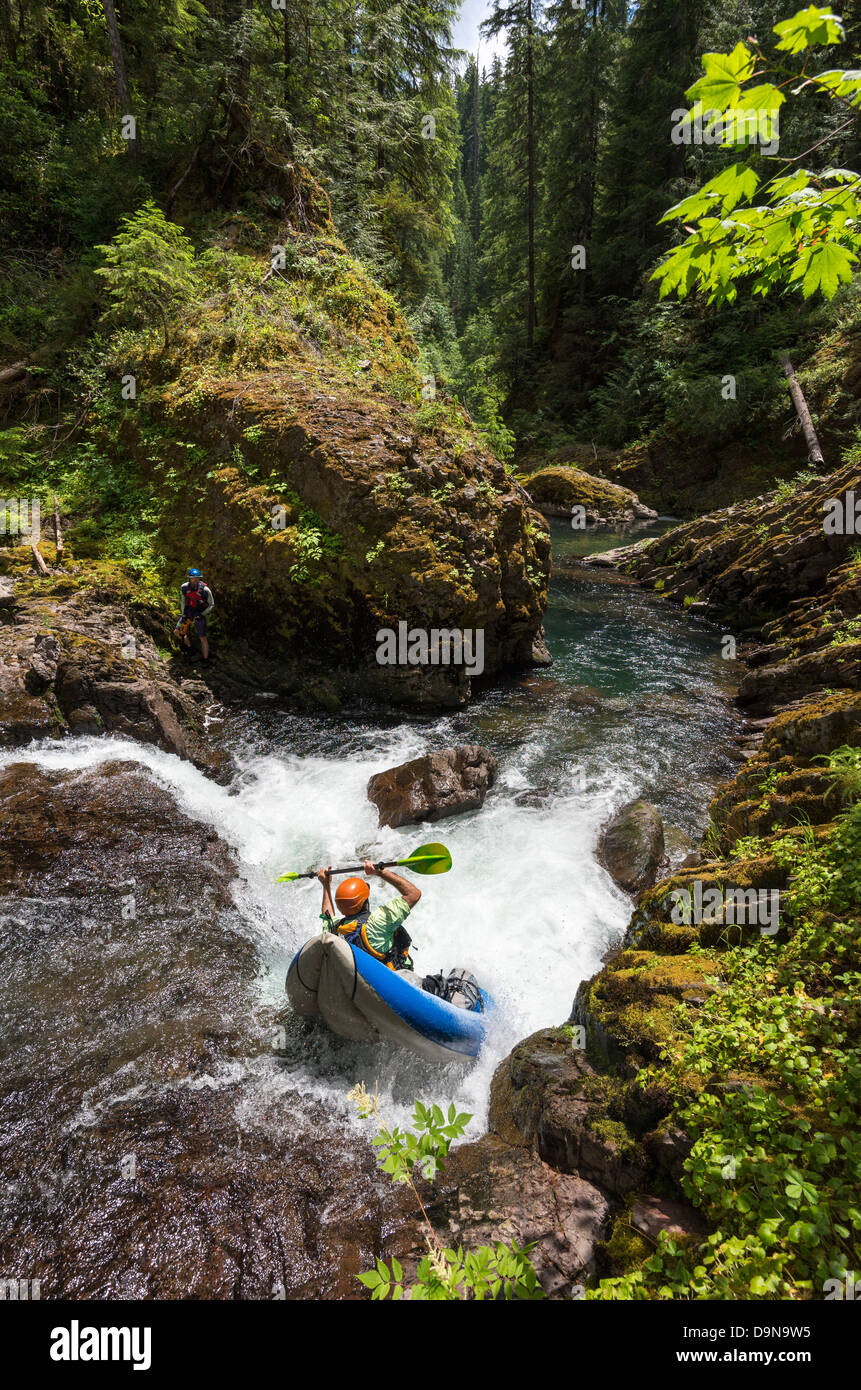 Paddling an inflatable kayak down a small waterfall on the Blue River in the Cascade Range of Oregon. Stock Photo