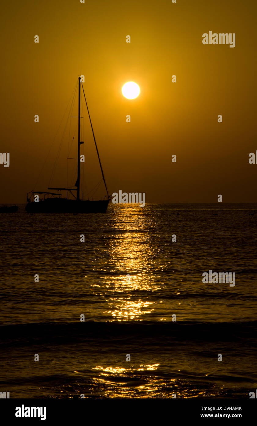 Setting sun on a Malta beach with a moored yacht  in the foreground Stock Photo