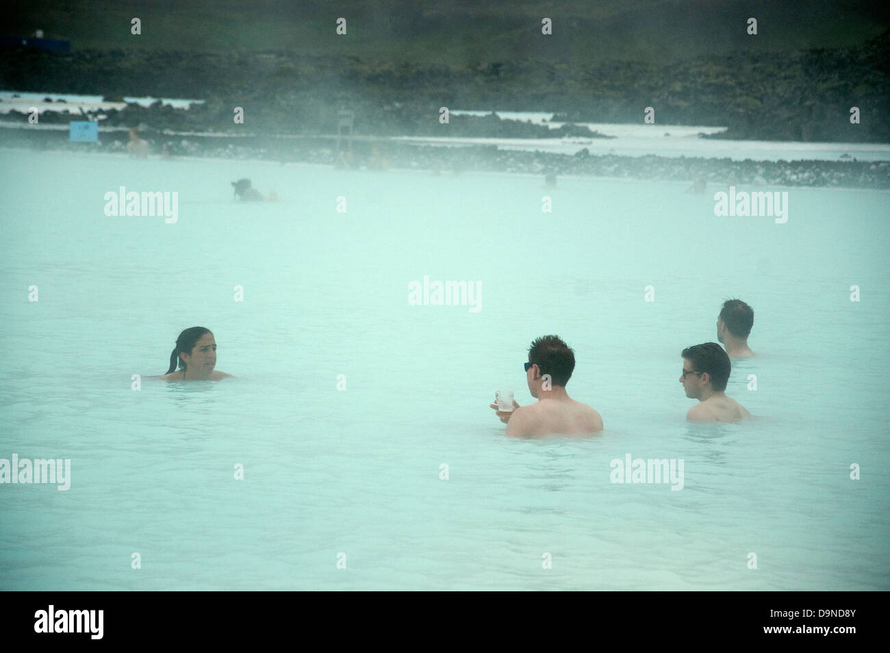 Relaxed swimmers, one with a glass in his hand, in the steamy turquoise waters of Iceland's Blue Lagoon Stock Photo