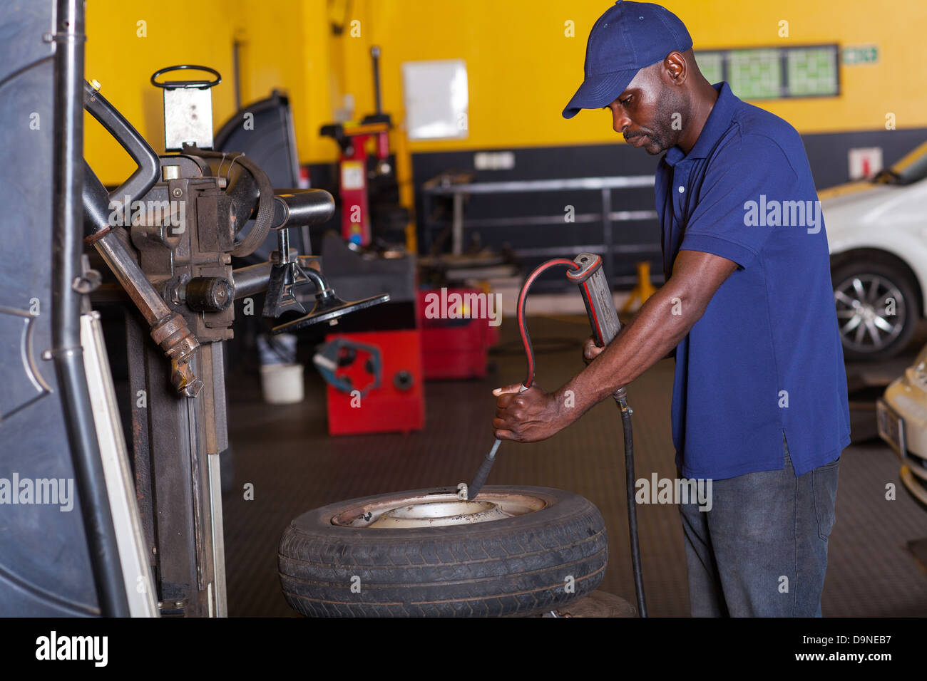African auto mechanic pumping car tyre Stock Photo Alamy