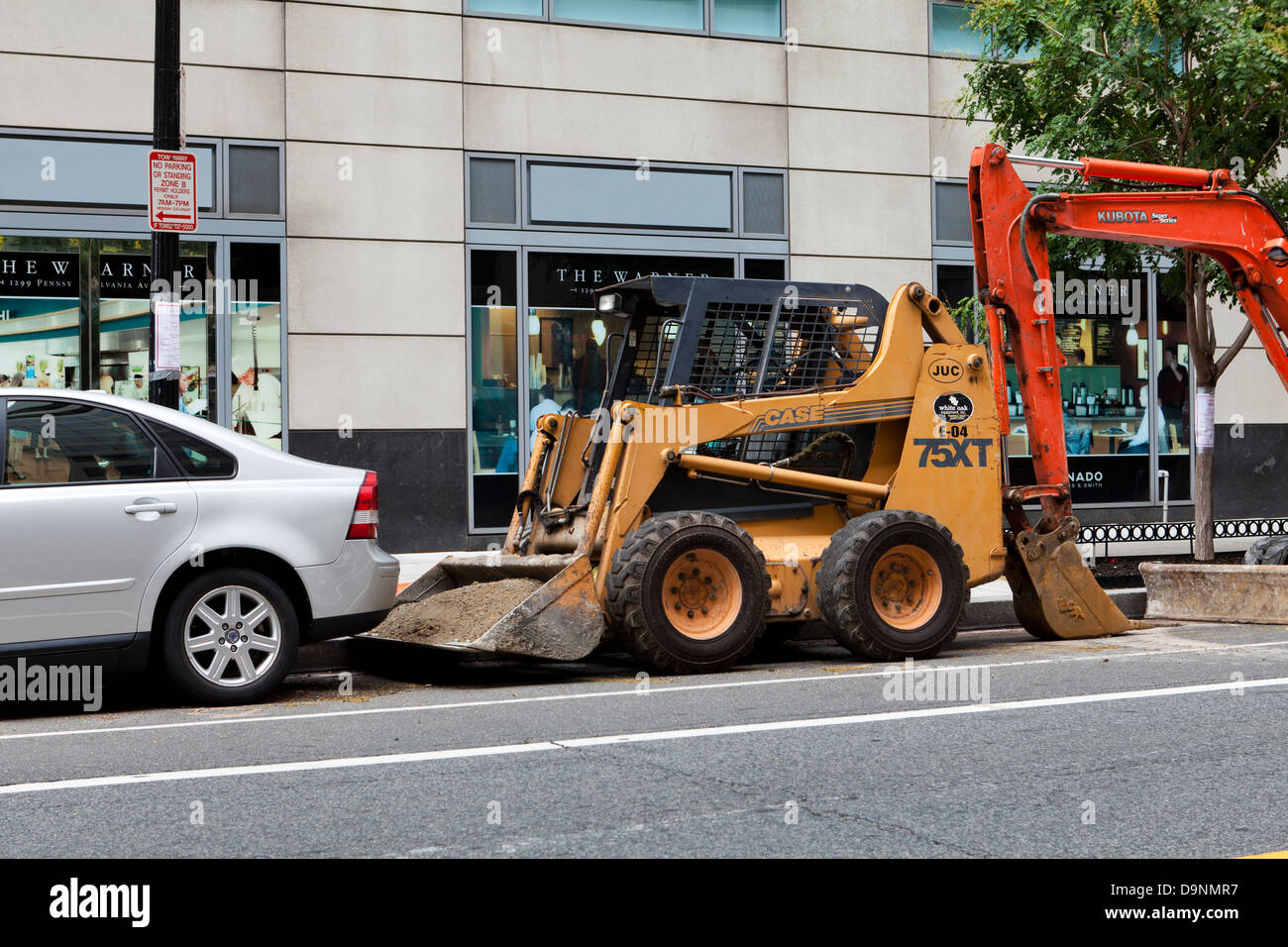 Front end loader and backhoe parked on city street Stock Photo