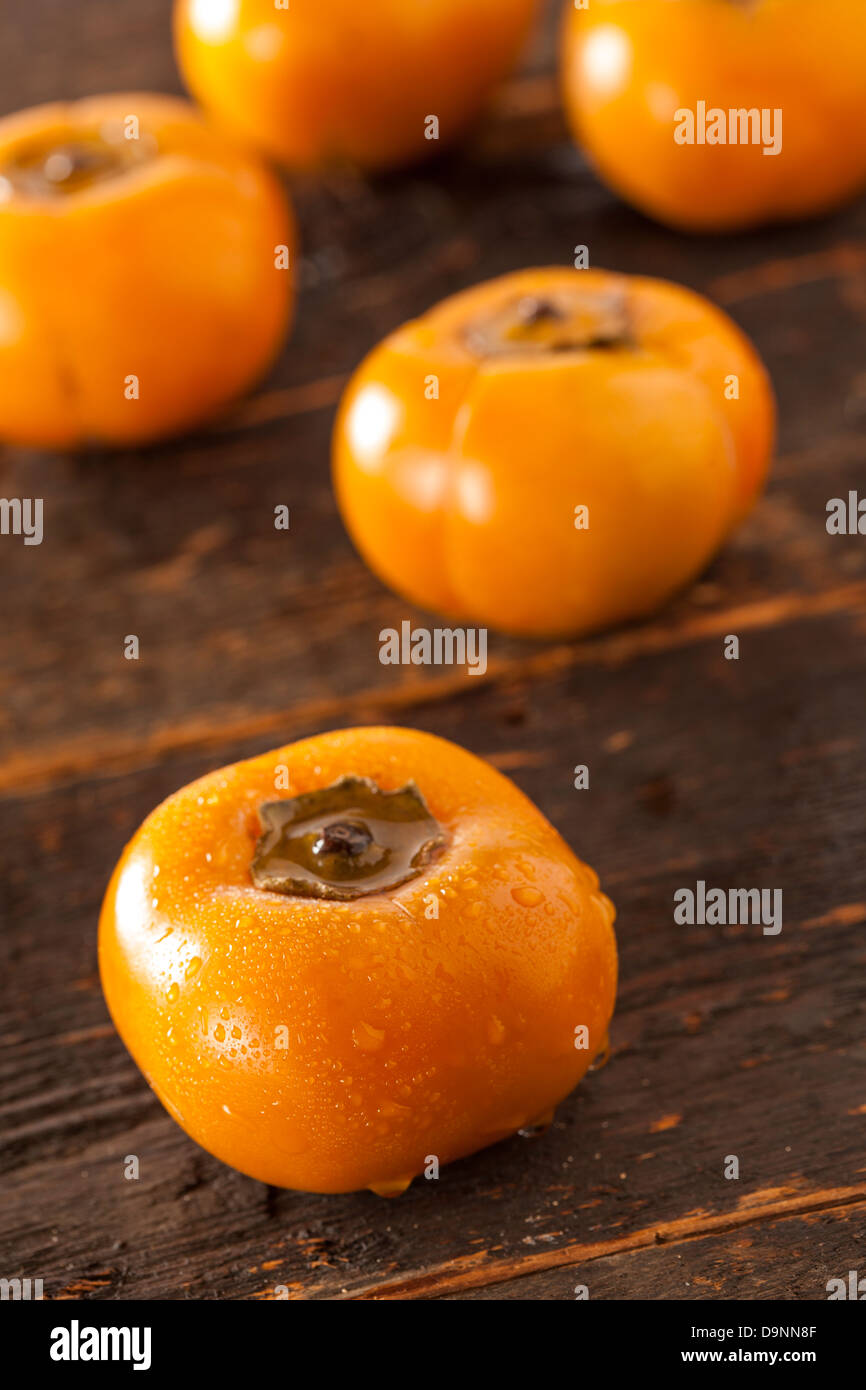 Organic Orange Persimmon Fruit against a background Stock Photo