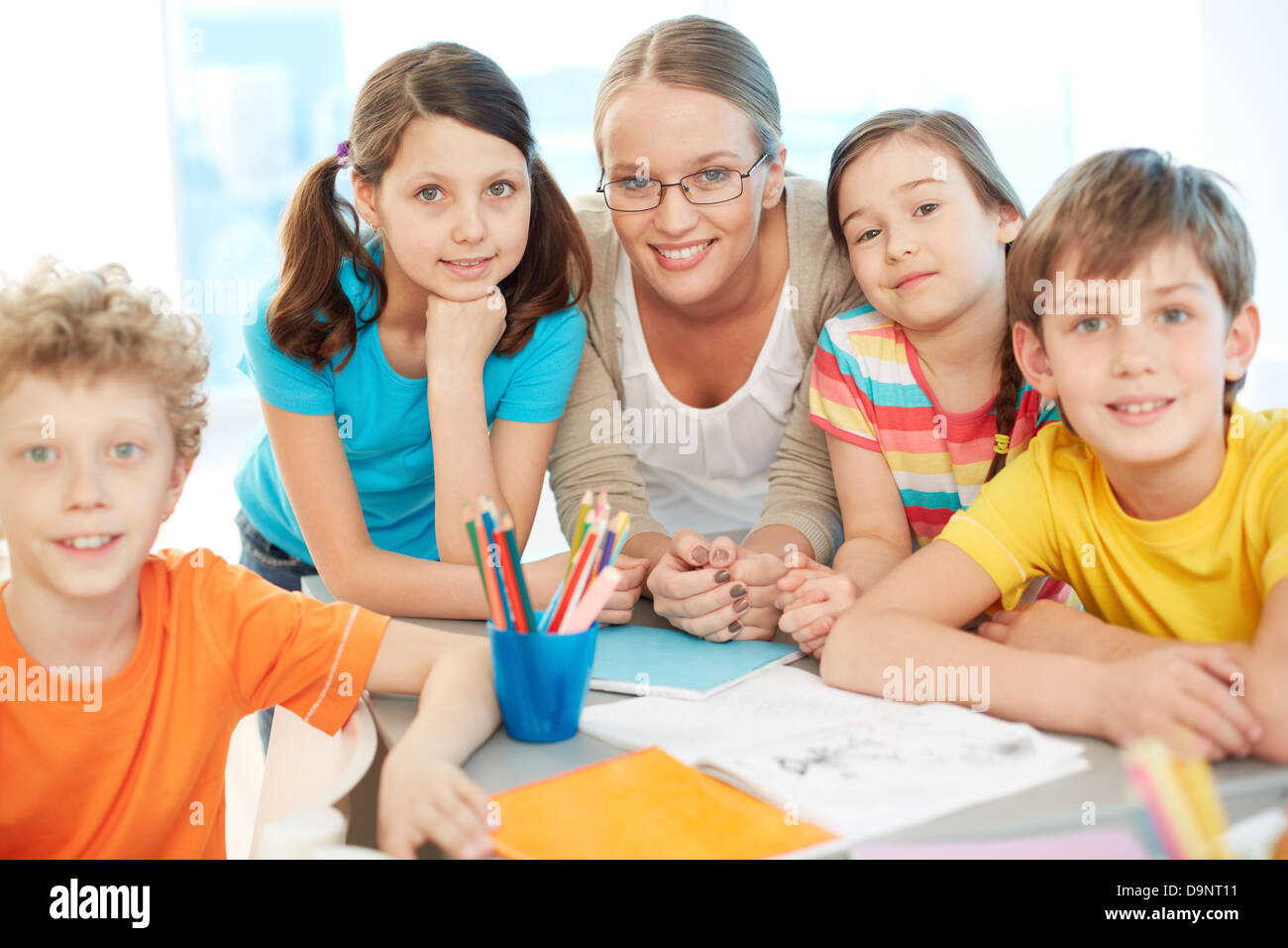 Portrait of diligent schoolkids and teacher looking at camera at lesson ...