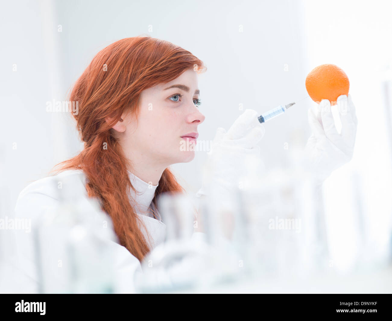 close-up of woman in a laboratory injecting an orange Stock Photo