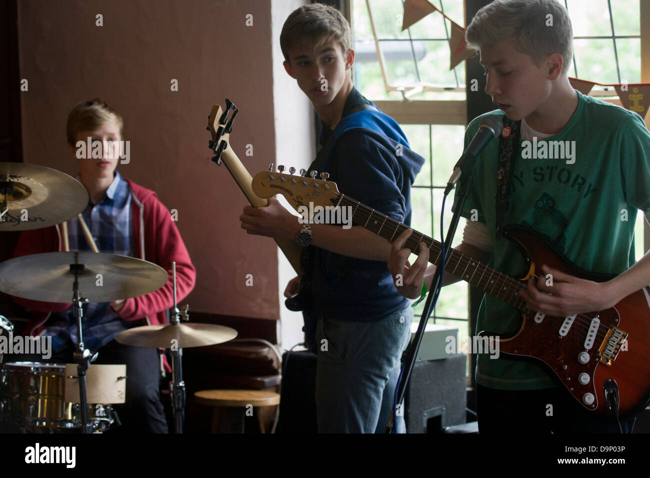A teenage band of drums, bass and lead guitar perform in front of ...