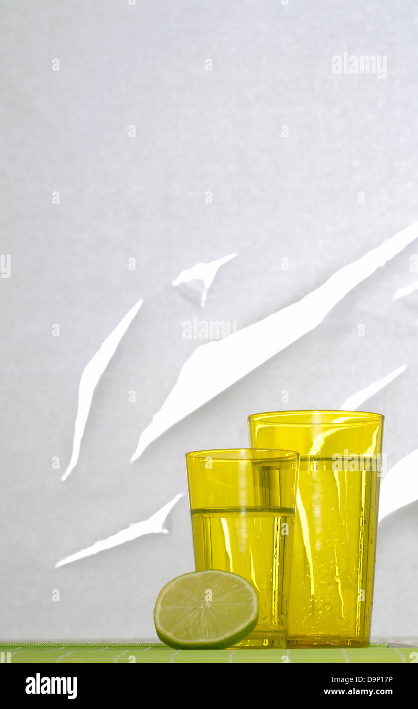 Half lemon in front of two drinking glasses Stock Photo