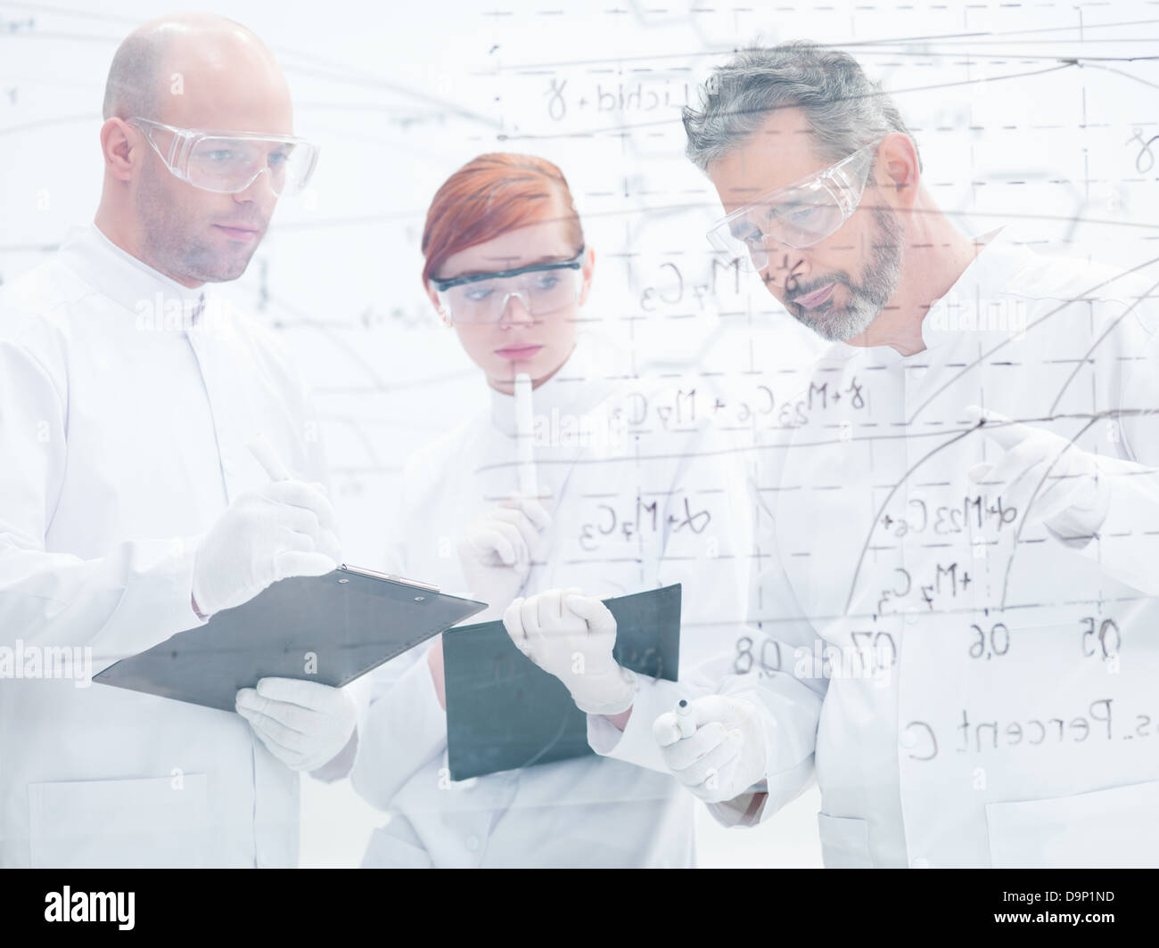 close-up of tree people in a laboratory analyzing data from a whiteboard Stock Photo