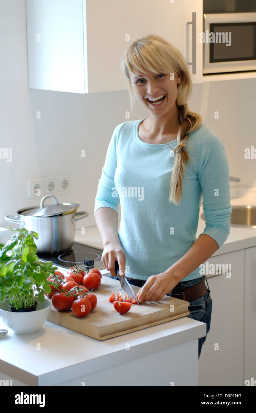Teenage girl slicing tomatoes in kitchen Stock Photo